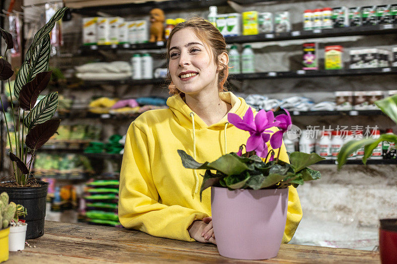 花店柜台上捧着花盆的中年花主/服务员